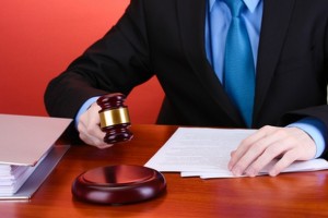 wooden gavel in hand and books on wooden table on red background